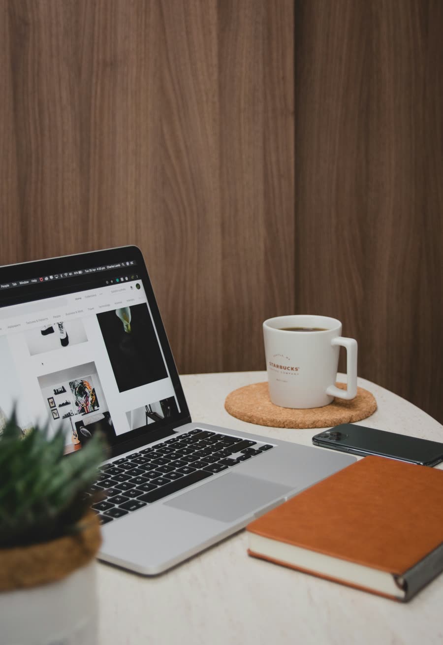 Tasse Kaffee, Laptop und Notizbuch auf einem Holztisch